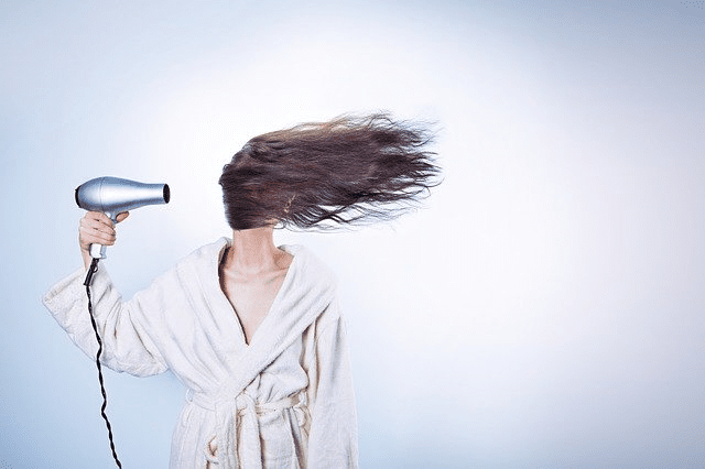 Hair Loss with Hypothyroidism gentle care. Woman pointing a hairdryer at her hair